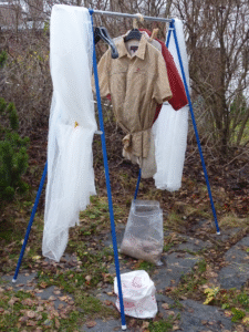 a white mosquito net and a couple of shirts hanging on a rack outside after being treated with permethrin
